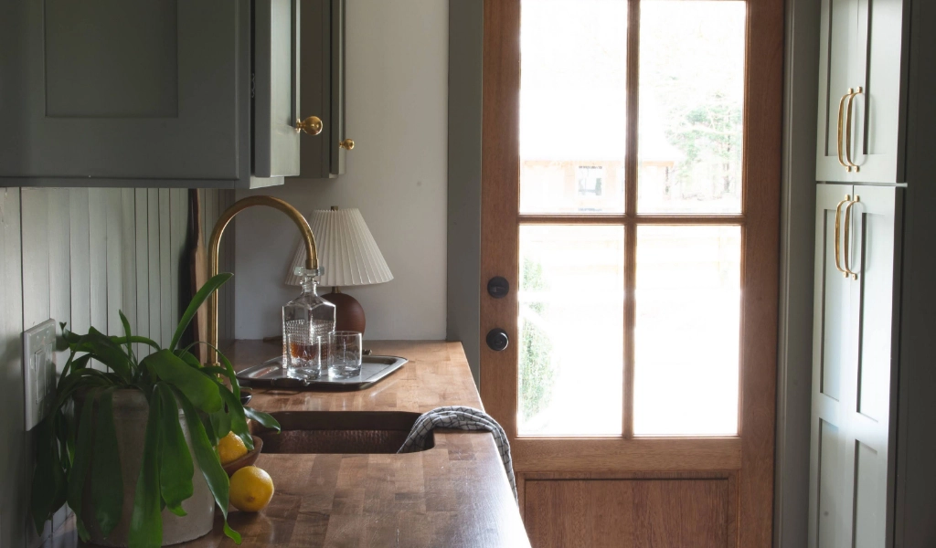 A kitchen with green cabinets and a wooden counter top.