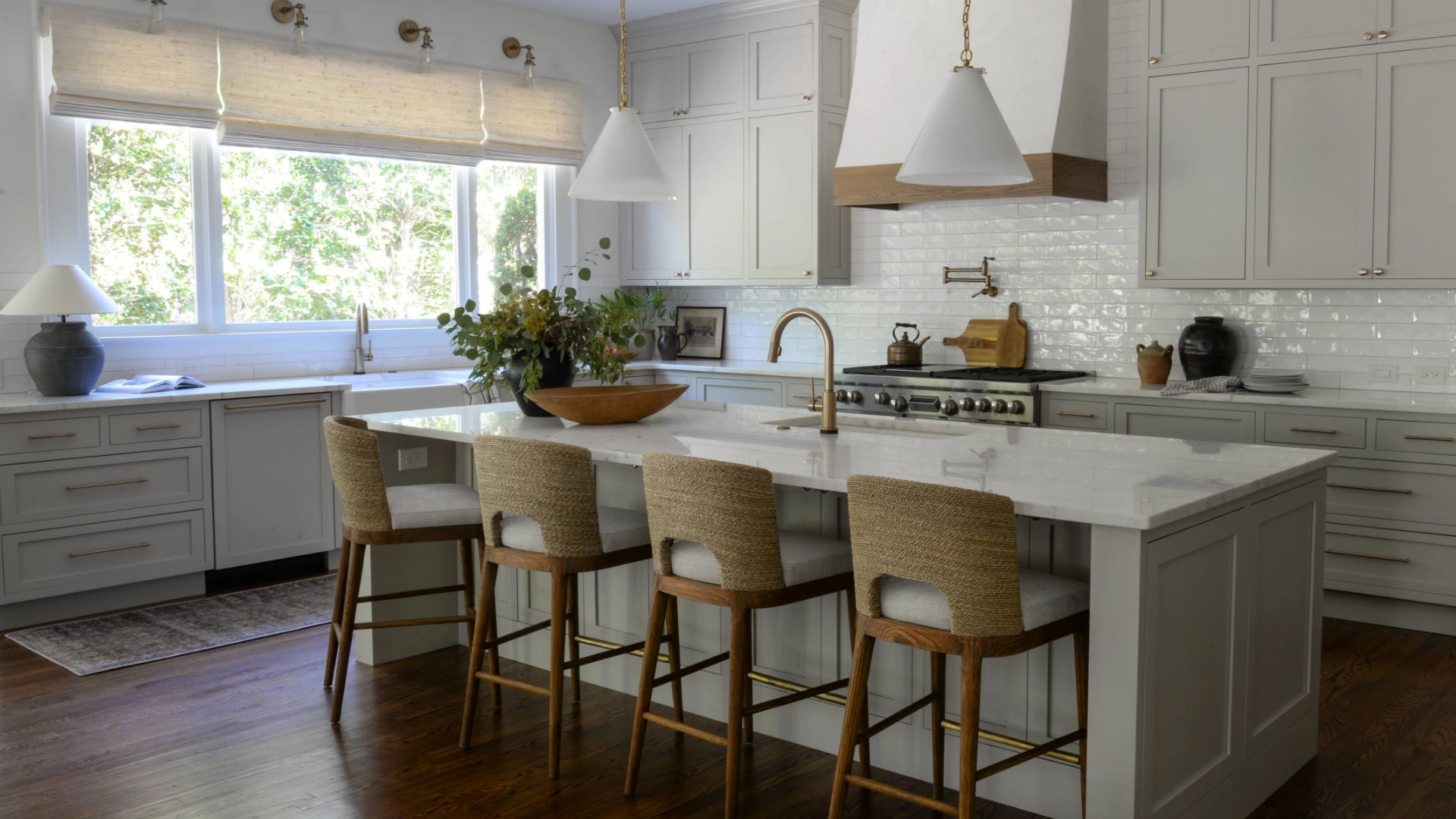 A white kitchen with a center island and stools in a custom-built home.