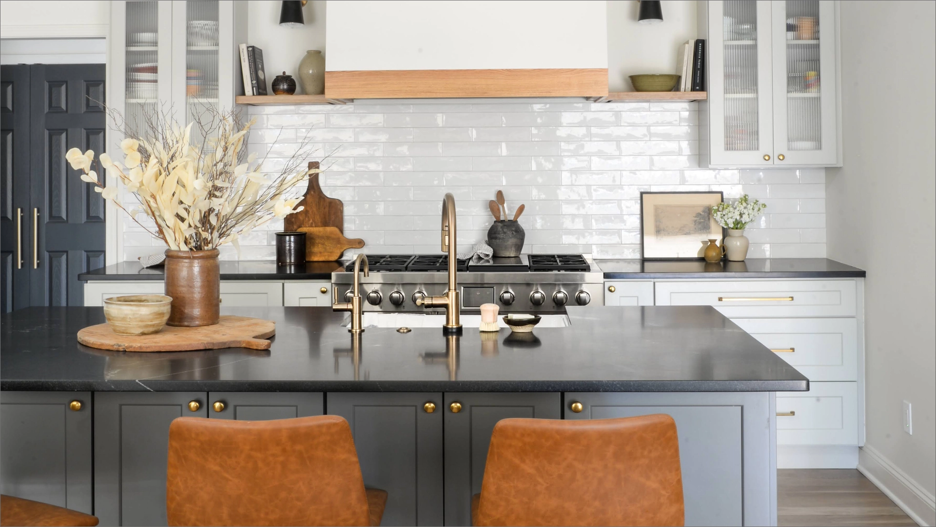 A modern kitchen with black and white tones and stylish brown leather stools.