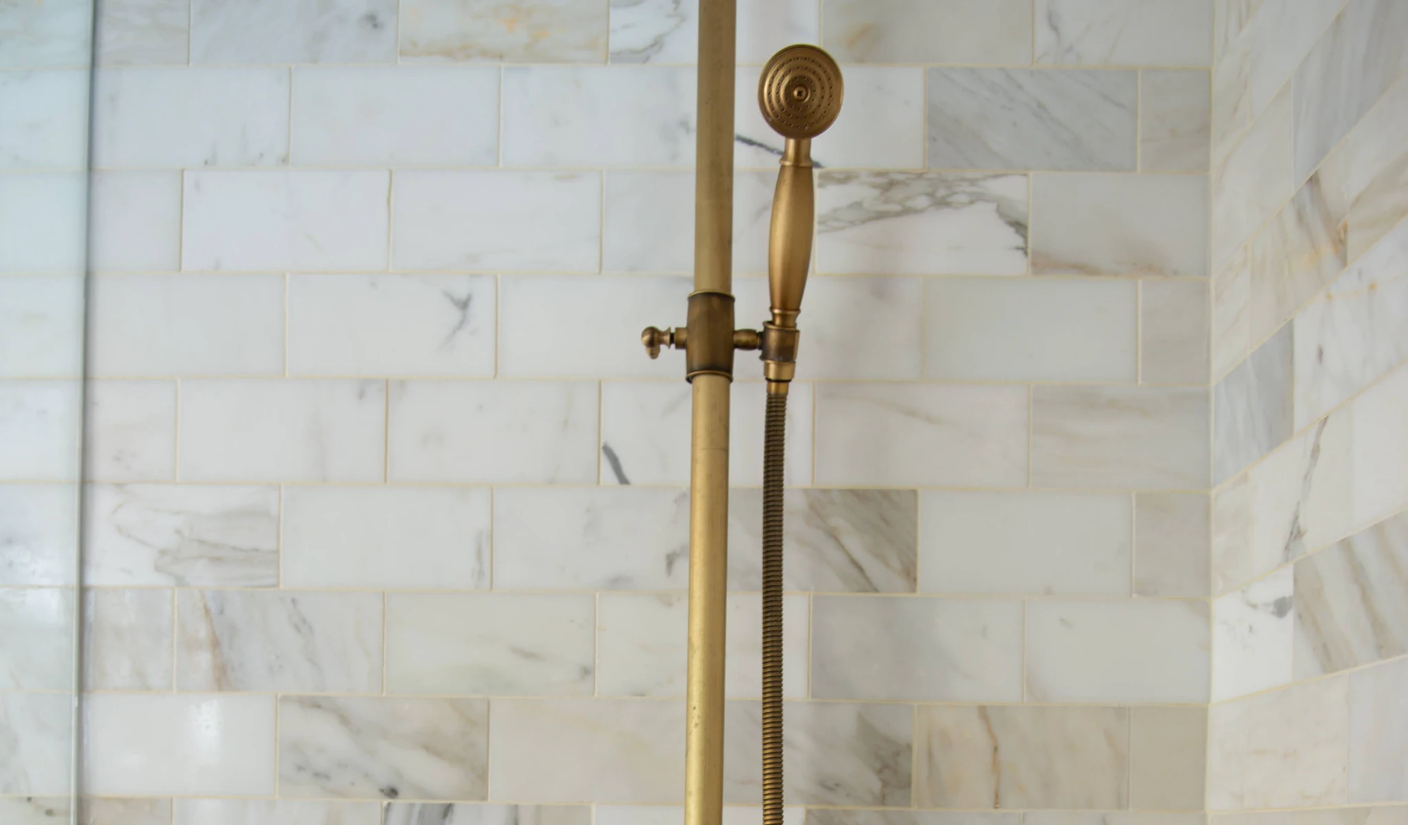 A shower with a brass shower head in a new home construction.