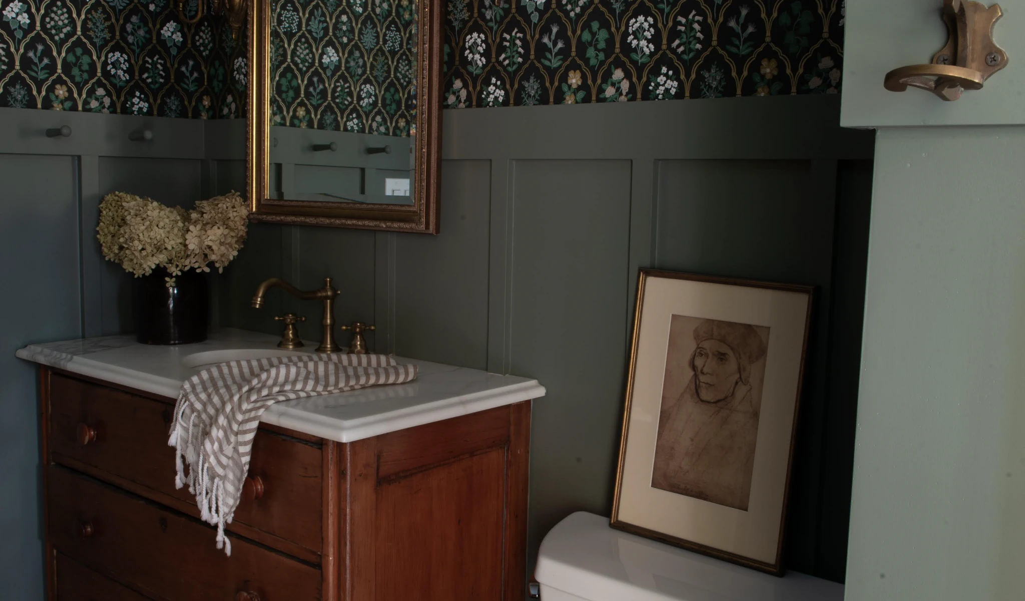 A bathroom with green wallpaper and a mirror.