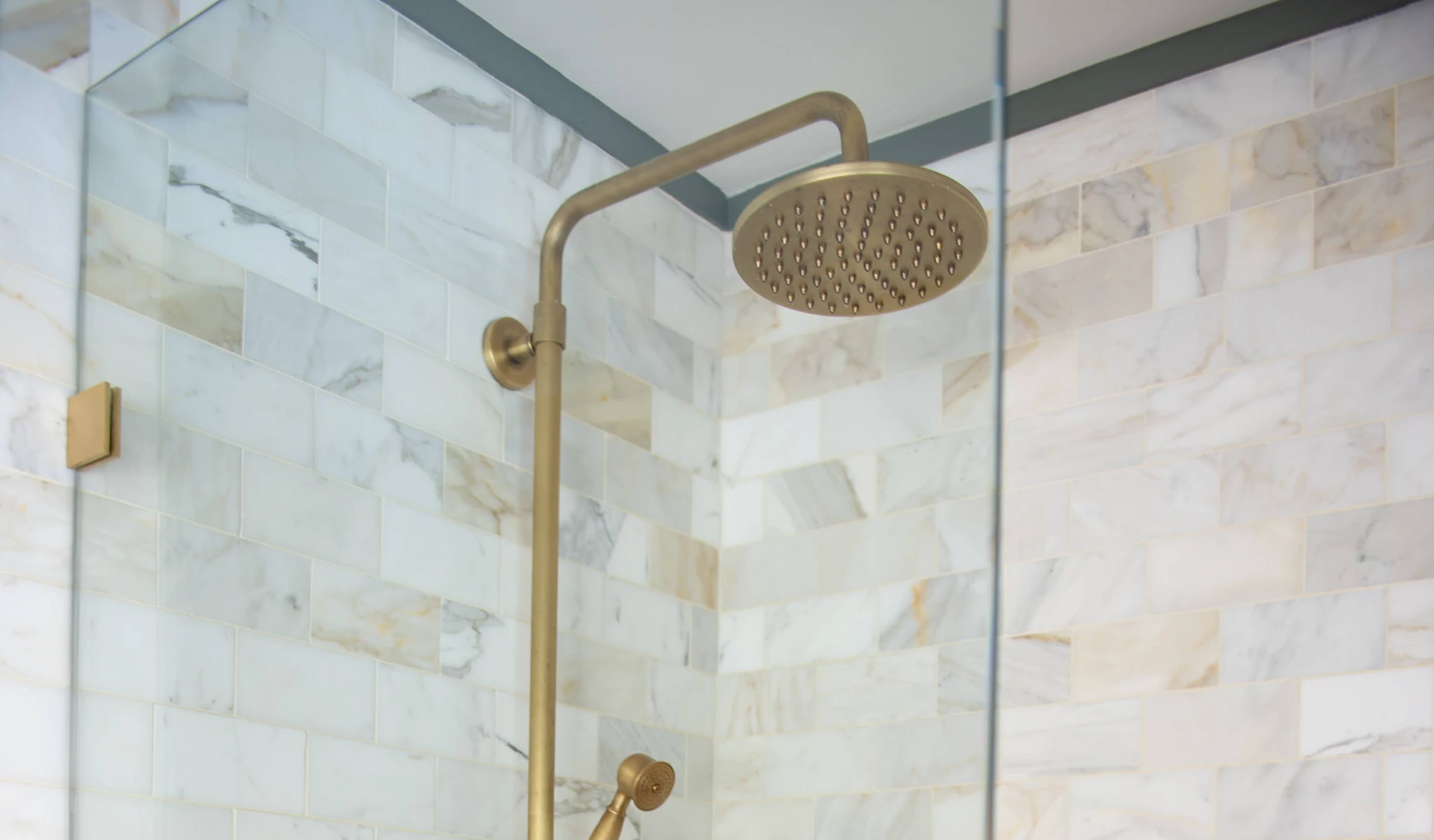 A shower with a brass shower head.