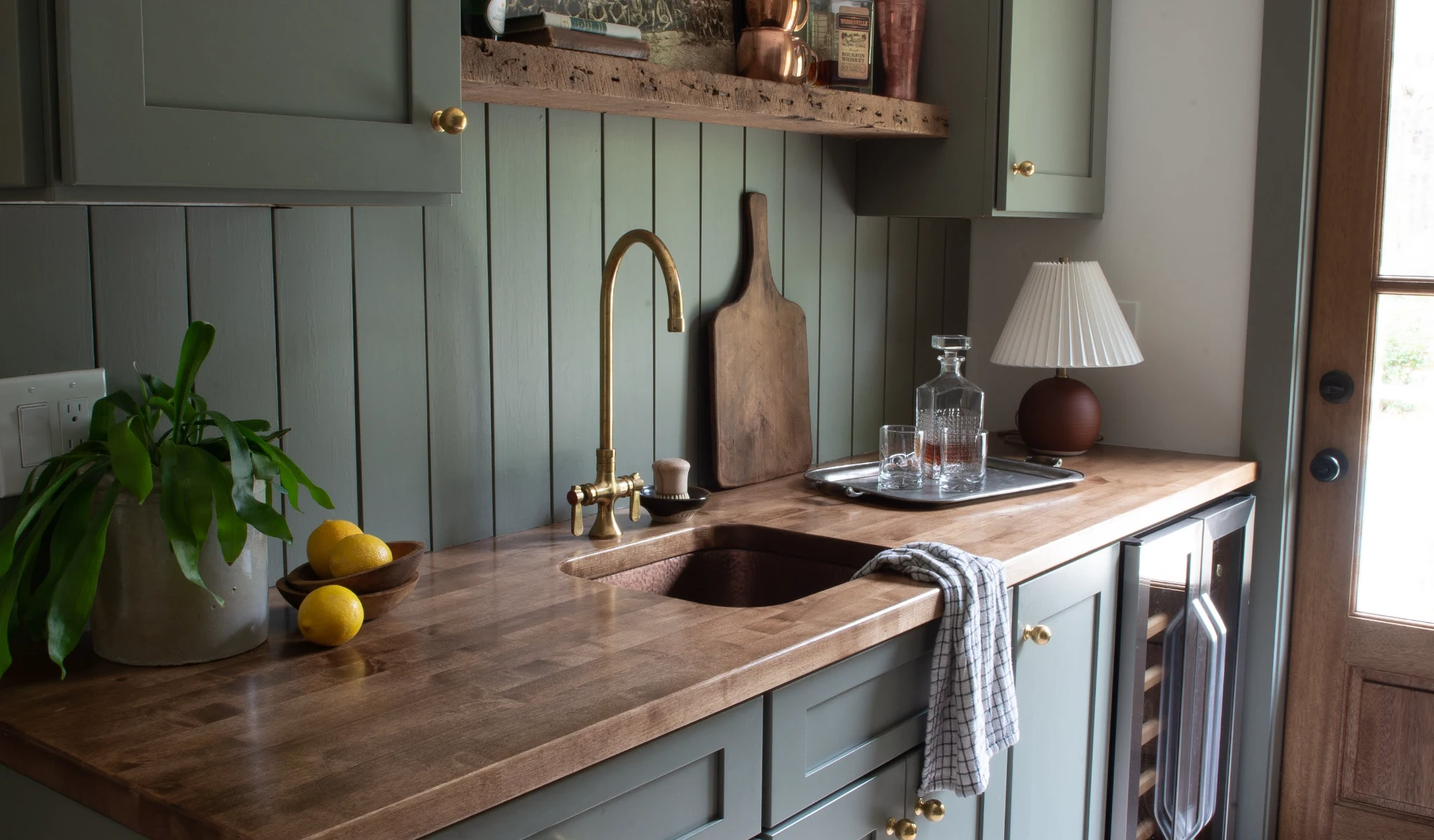 A new kitchen with green cabinets and a wooden counter top.