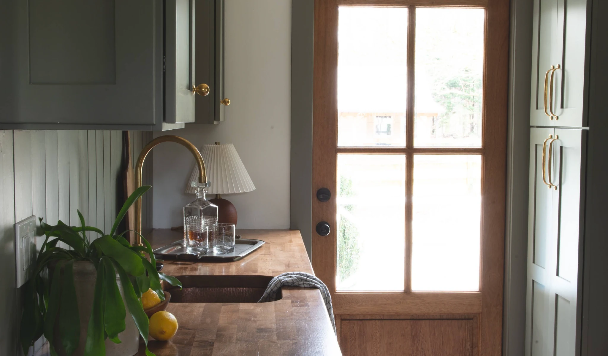 A kitchen with green cabinets and a wooden countertop.