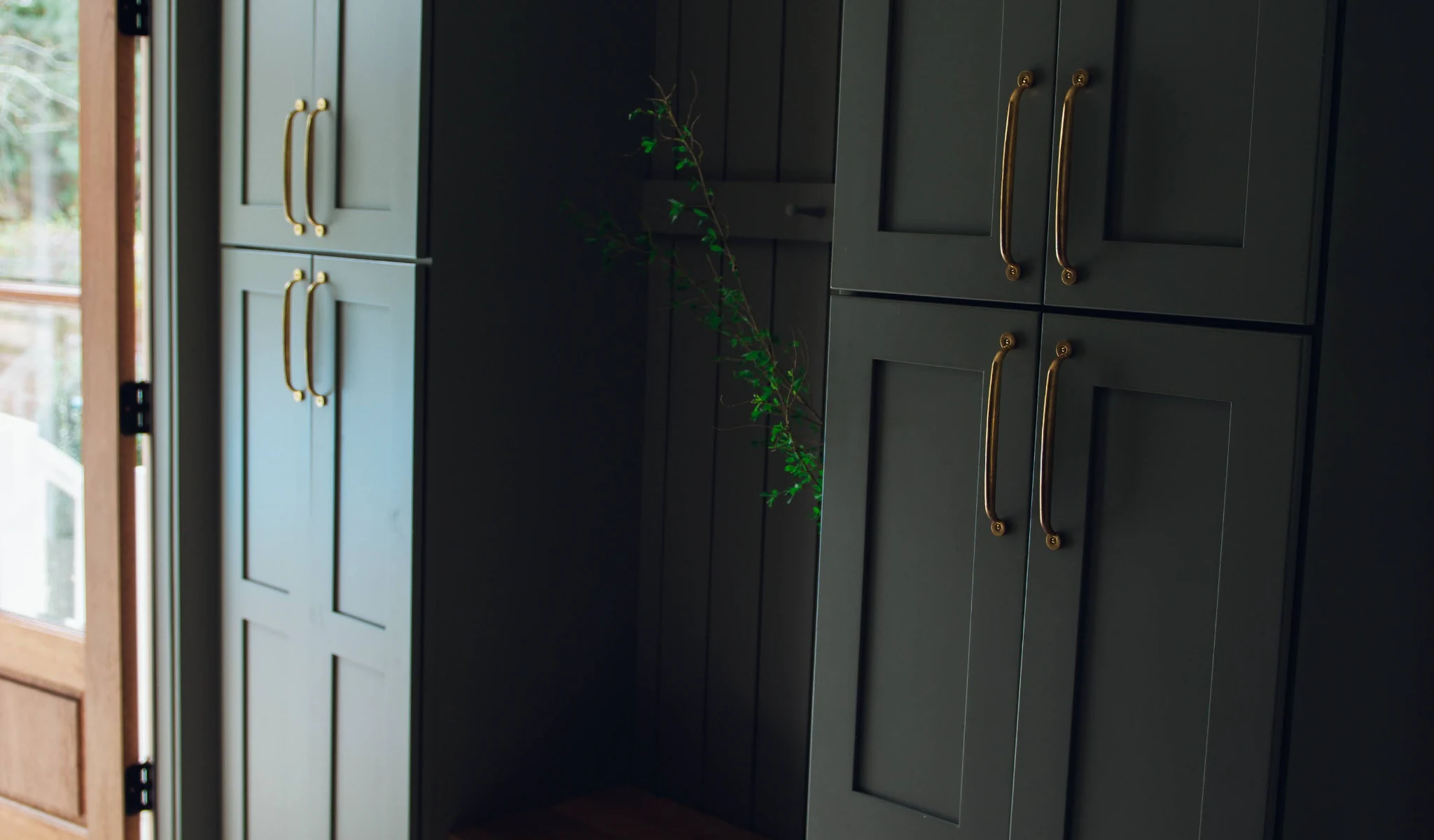 A black door with brass handles in a hallway of a new home construction.
