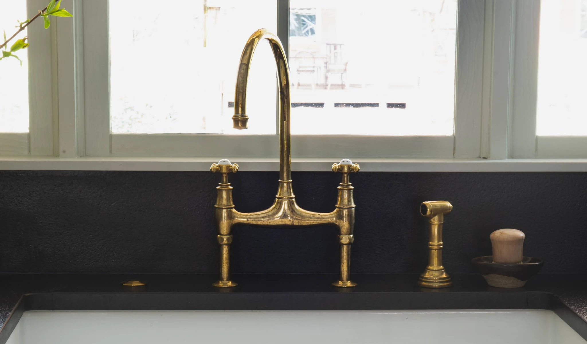 A black kitchen sink with a brass faucet.
