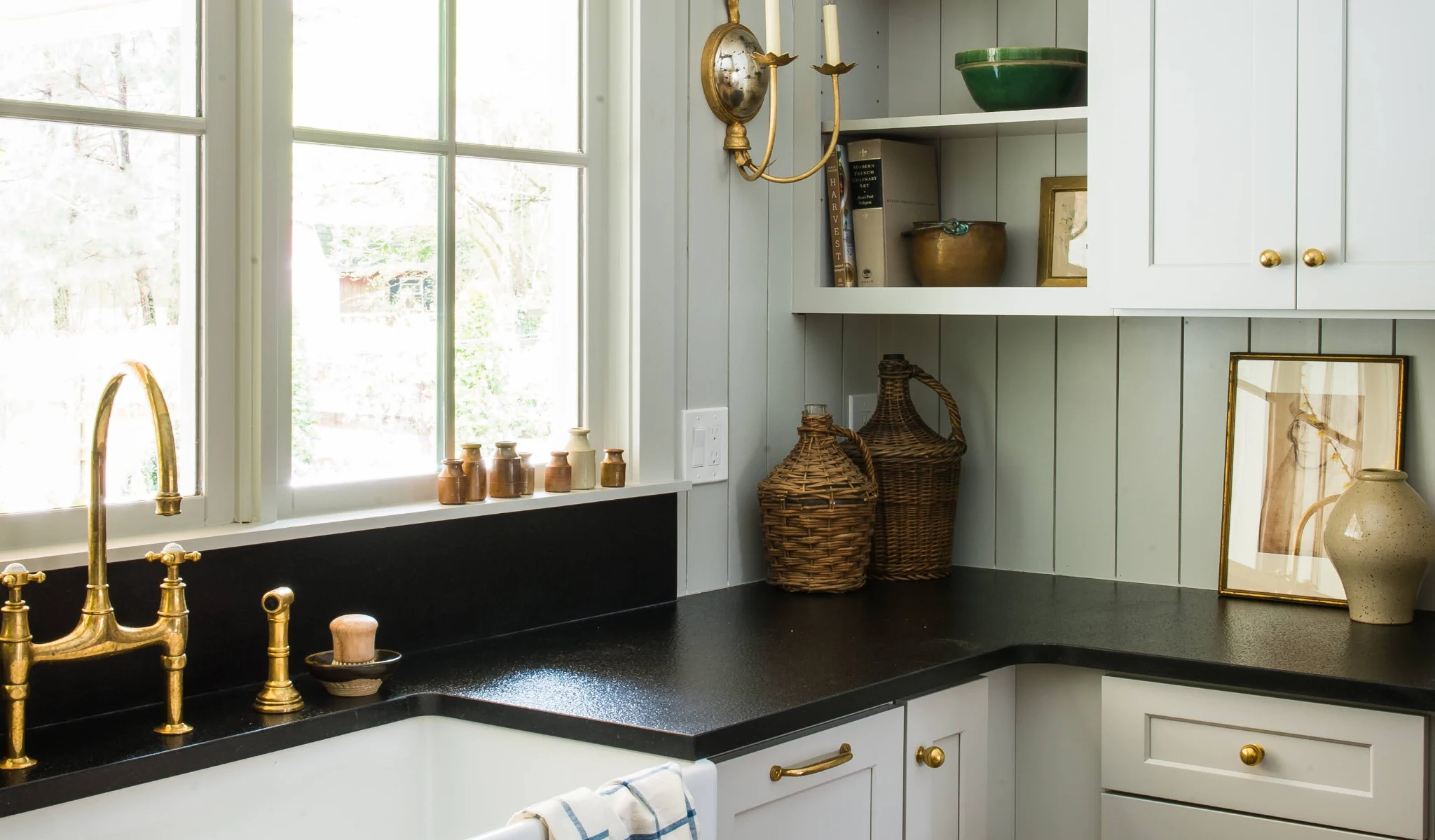 A white kitchen with black countertops and a window in a new home.