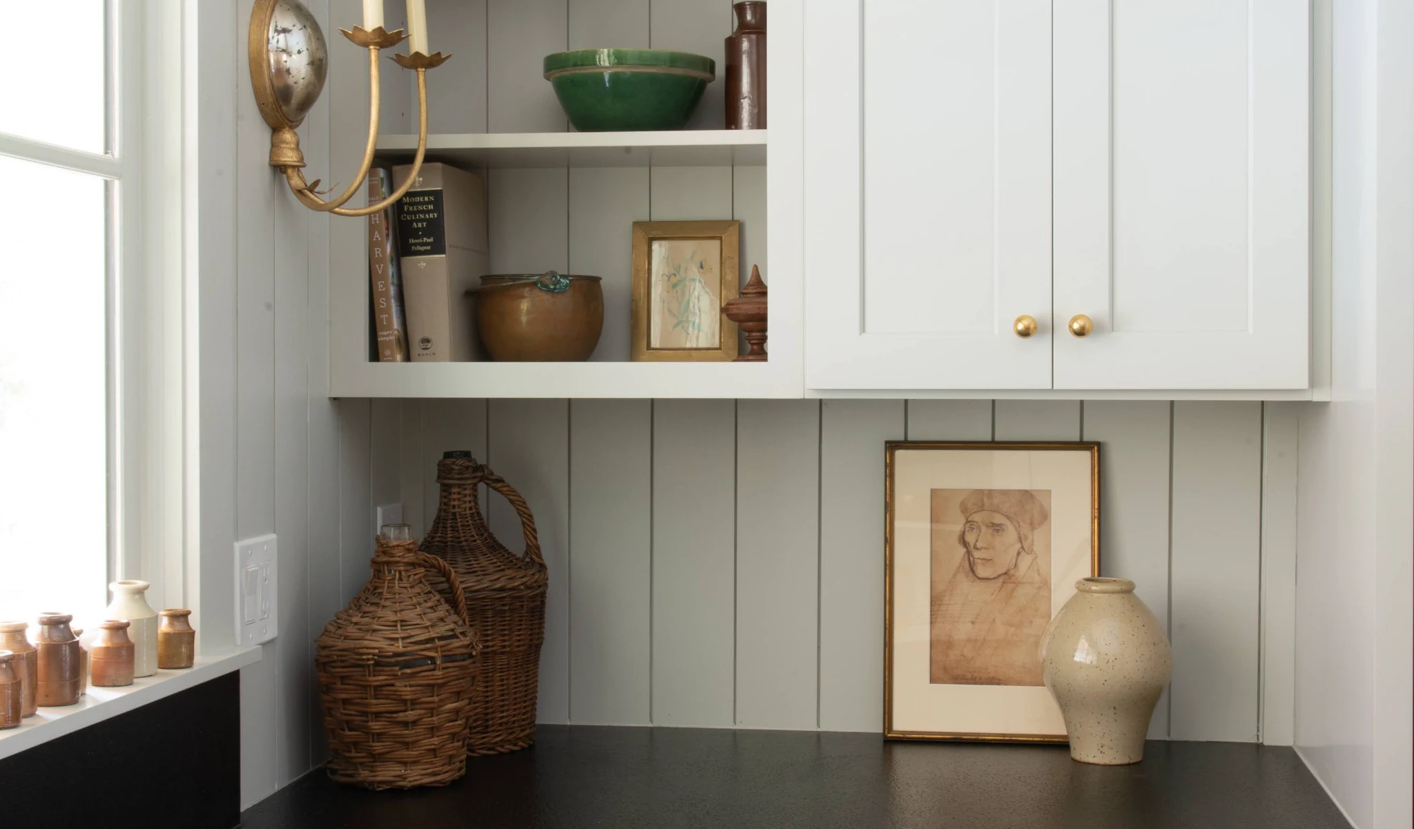 A kitchen with white cabinets and a black counter.