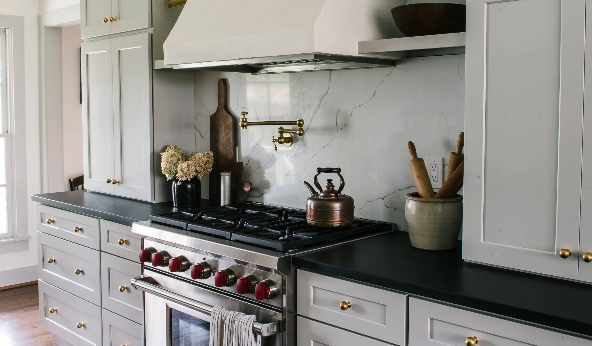 A kitchen with white cabinets and a black stovetop.