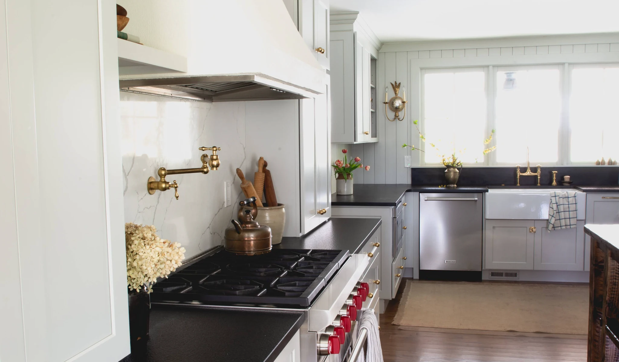 A kitchen with white cabinets and black countertops.