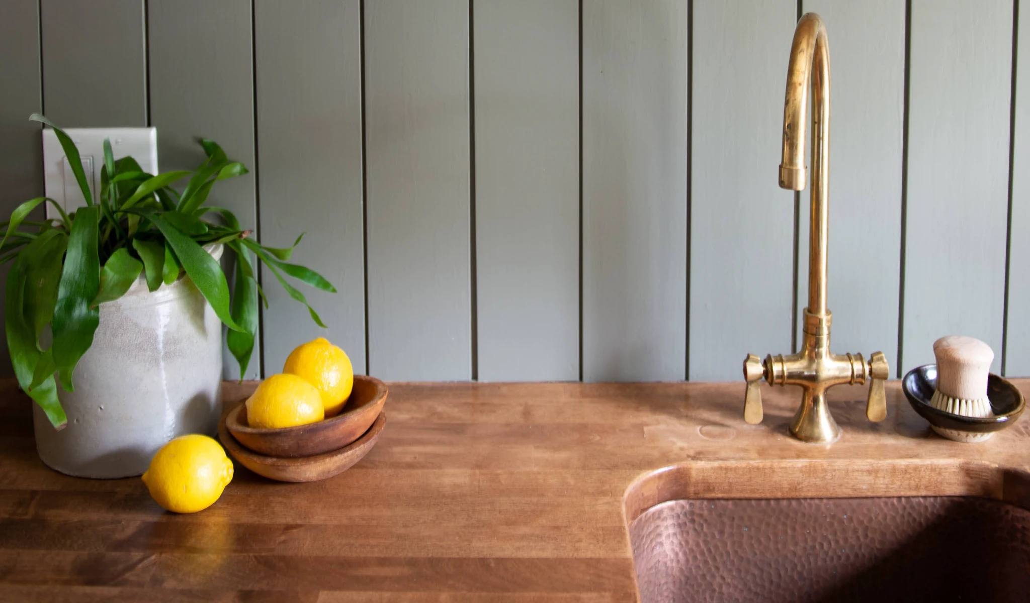 A kitchen with a copper sink and wooden counter.