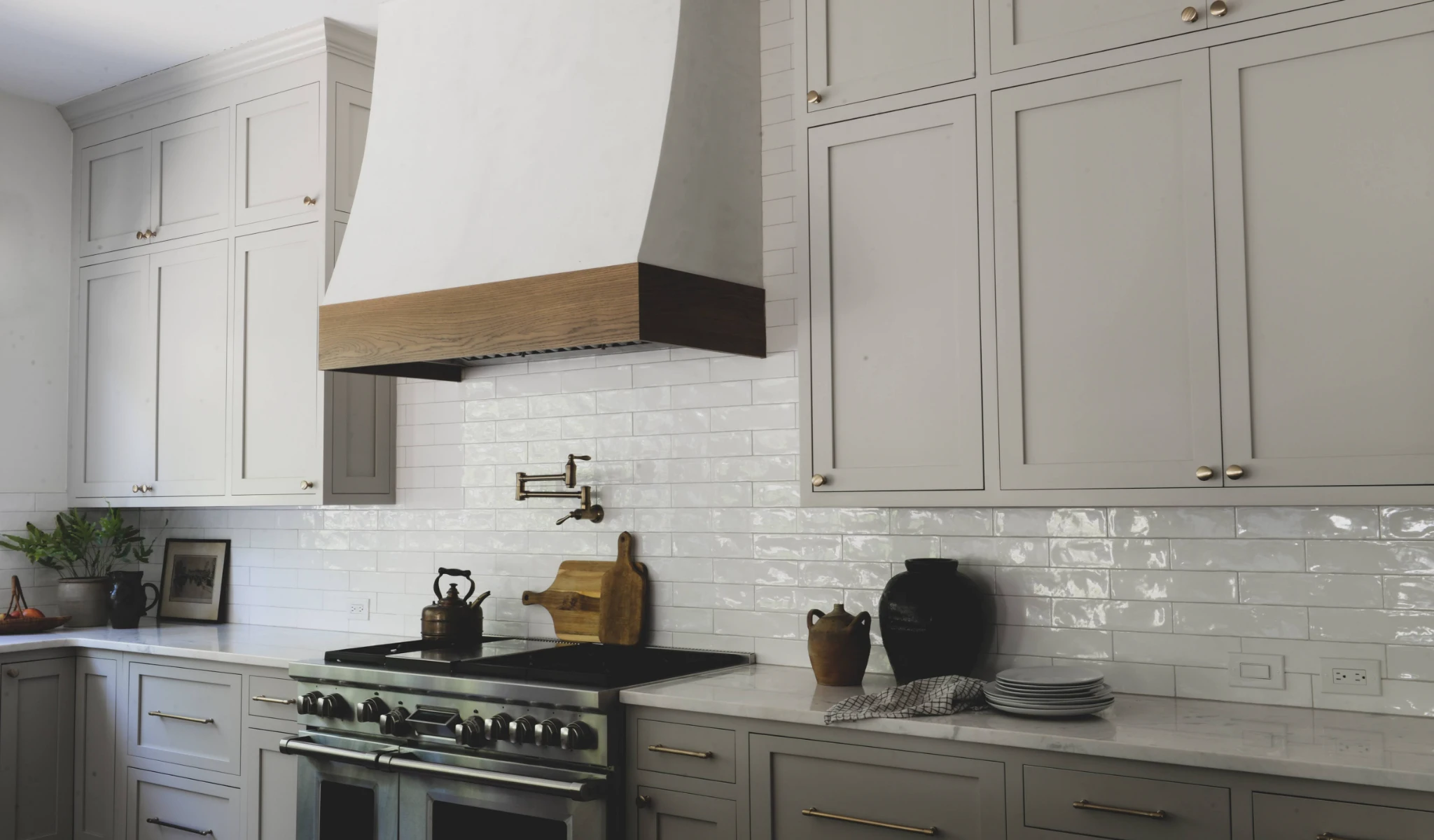A white kitchen with custom gray cabinets and a new stove.