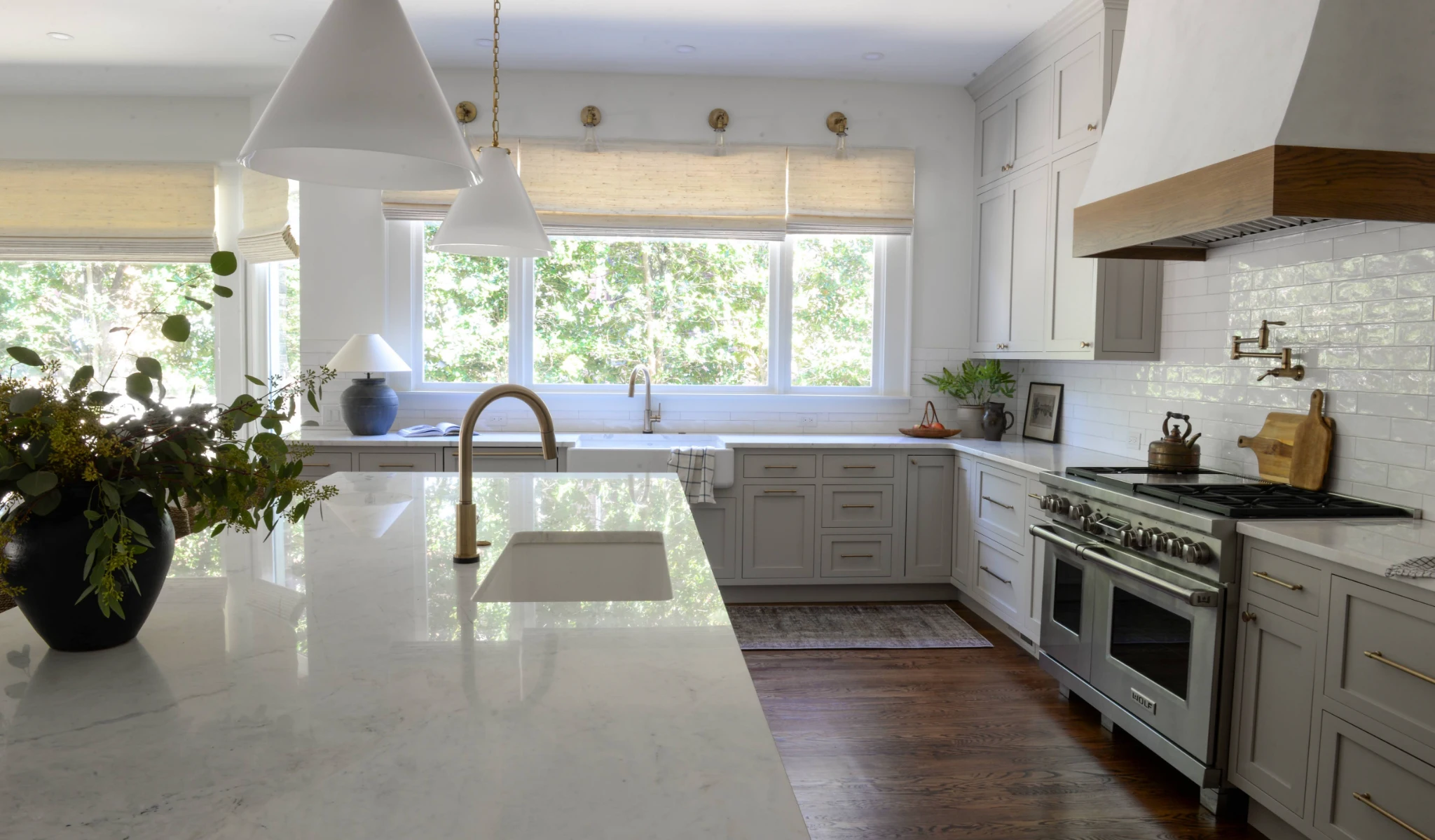 A white kitchen with marble counter tops and white cabinets designed by a custom home builder.