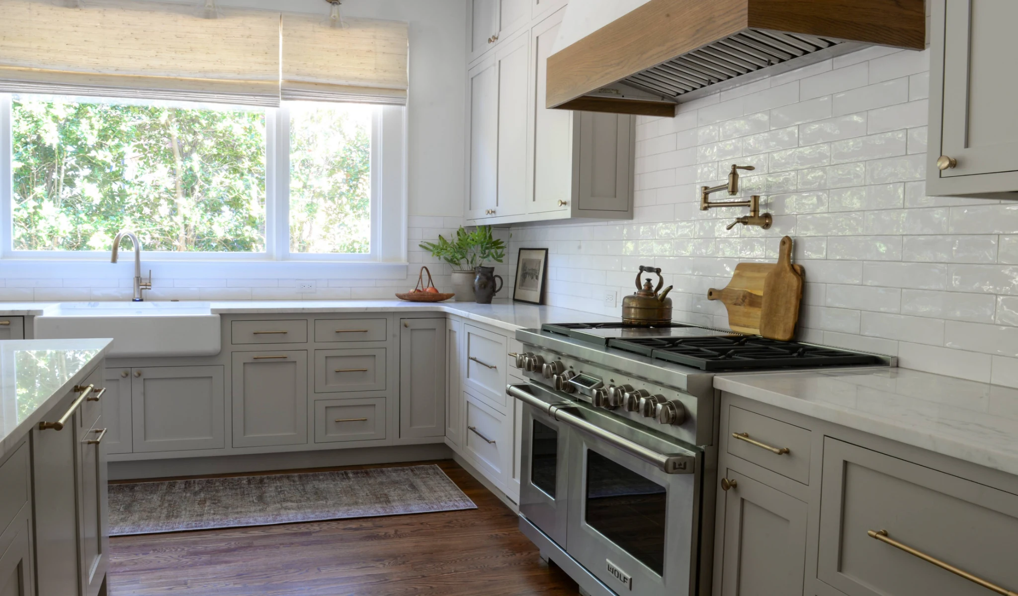 A kitchen with gray cabinets and wood floors.