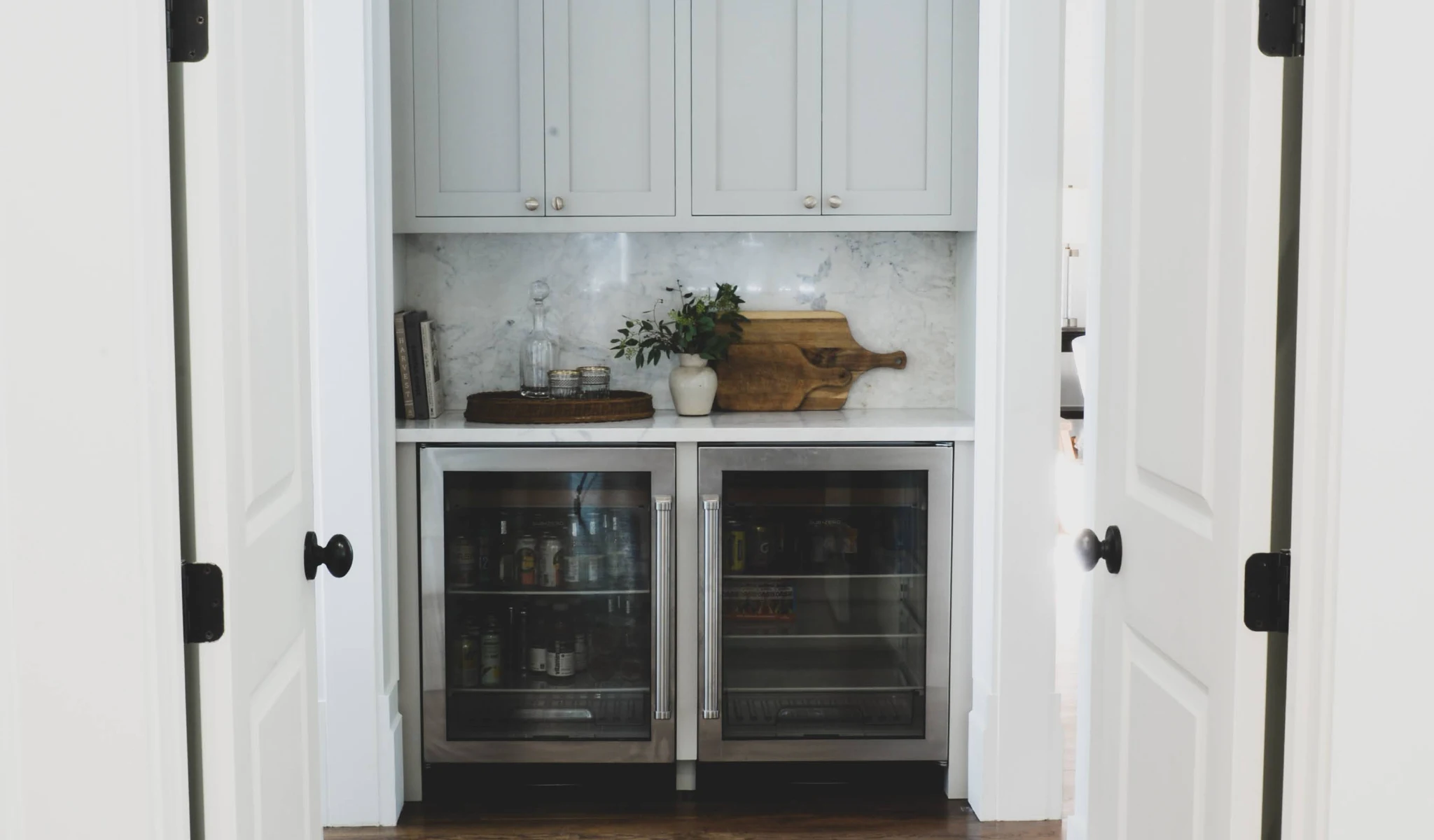 A white kitchen with a refrigerator in the doorway designed by a home designer.
