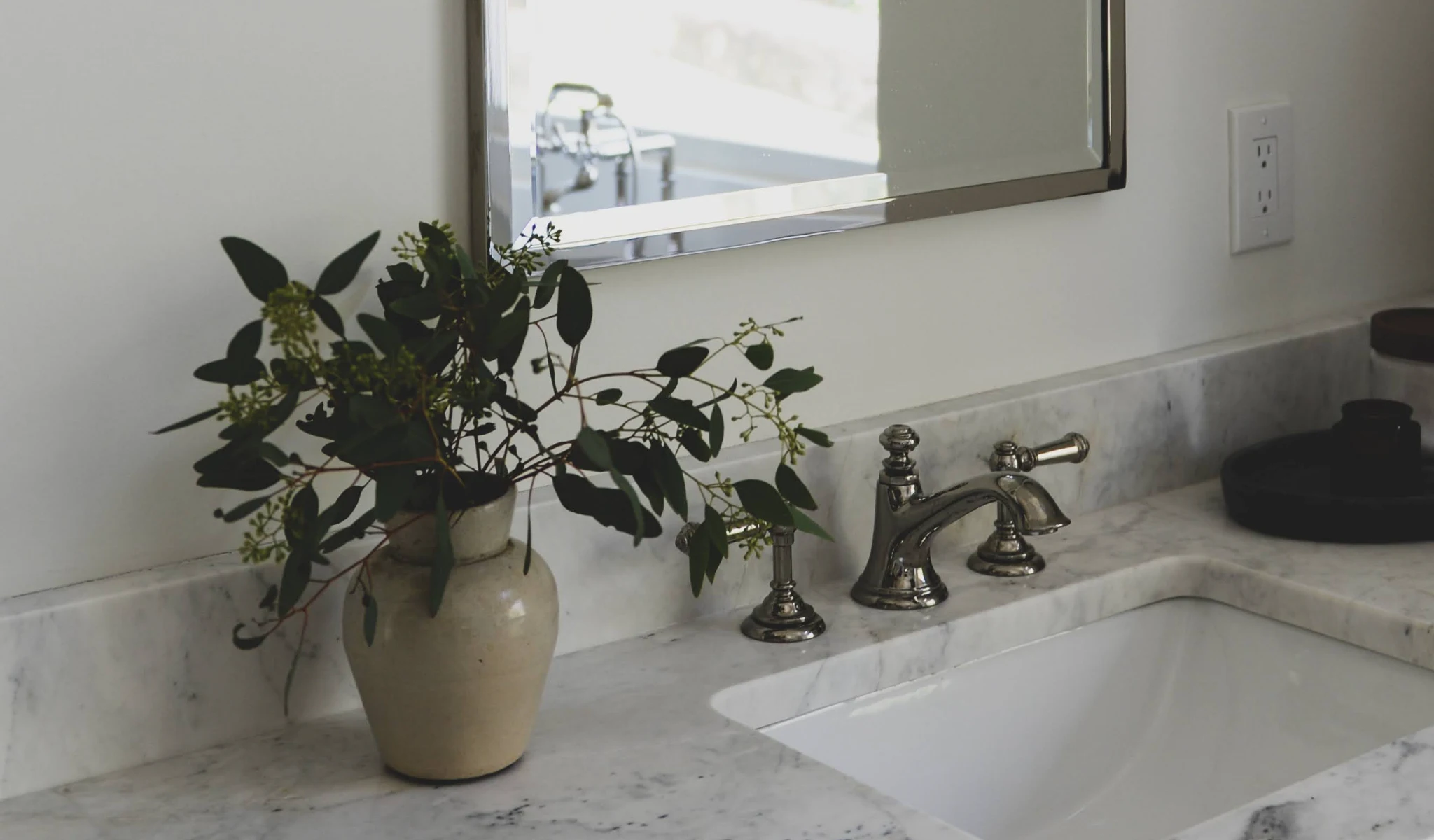 A bathroom sink with a vase of flowers.