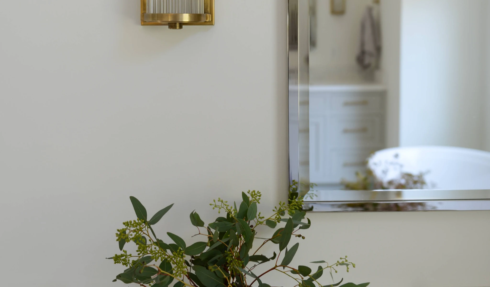 A bathroom with a mirror and a potted plant.
