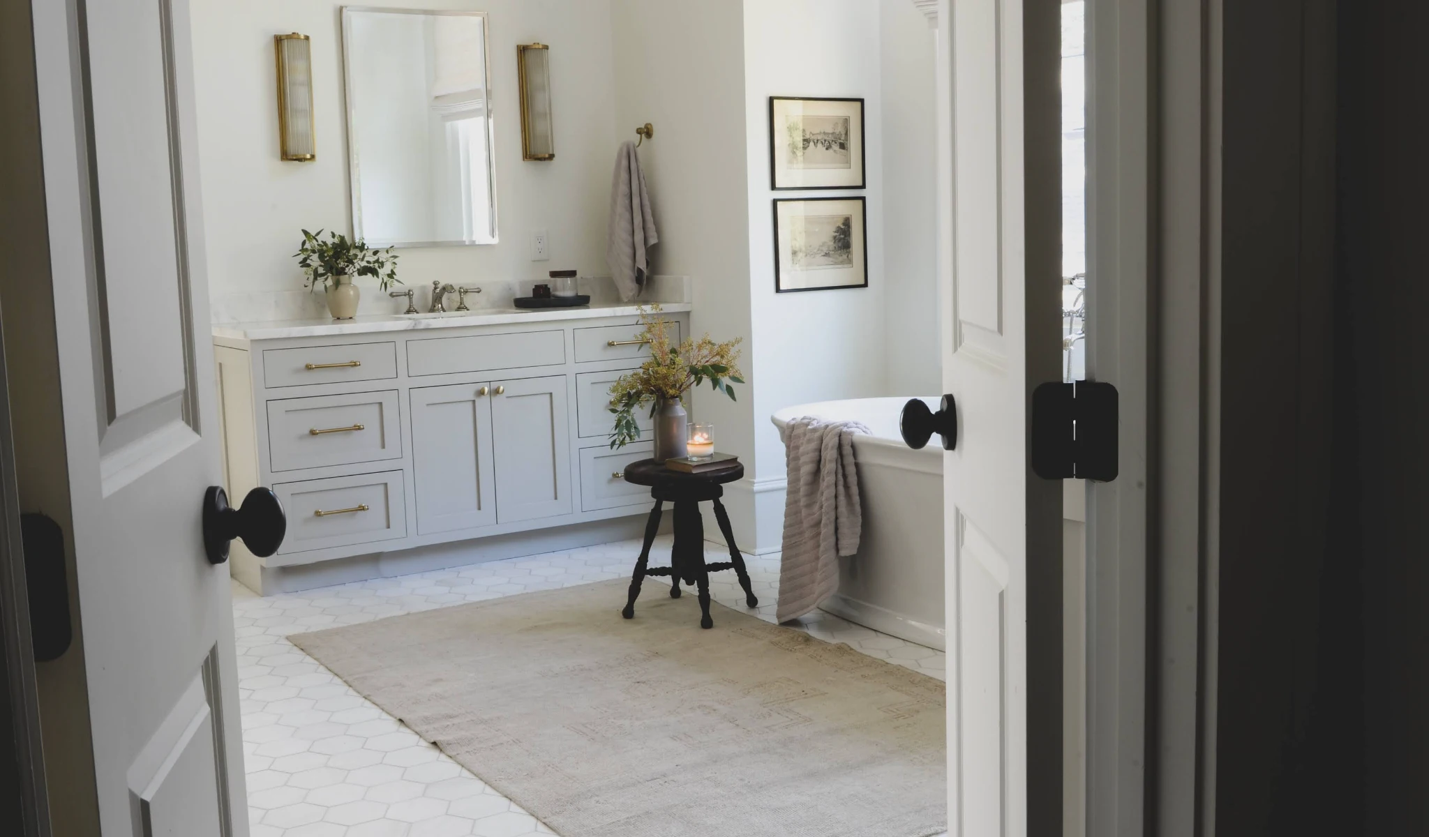 A white bathroom with black and gold accents and a tub.