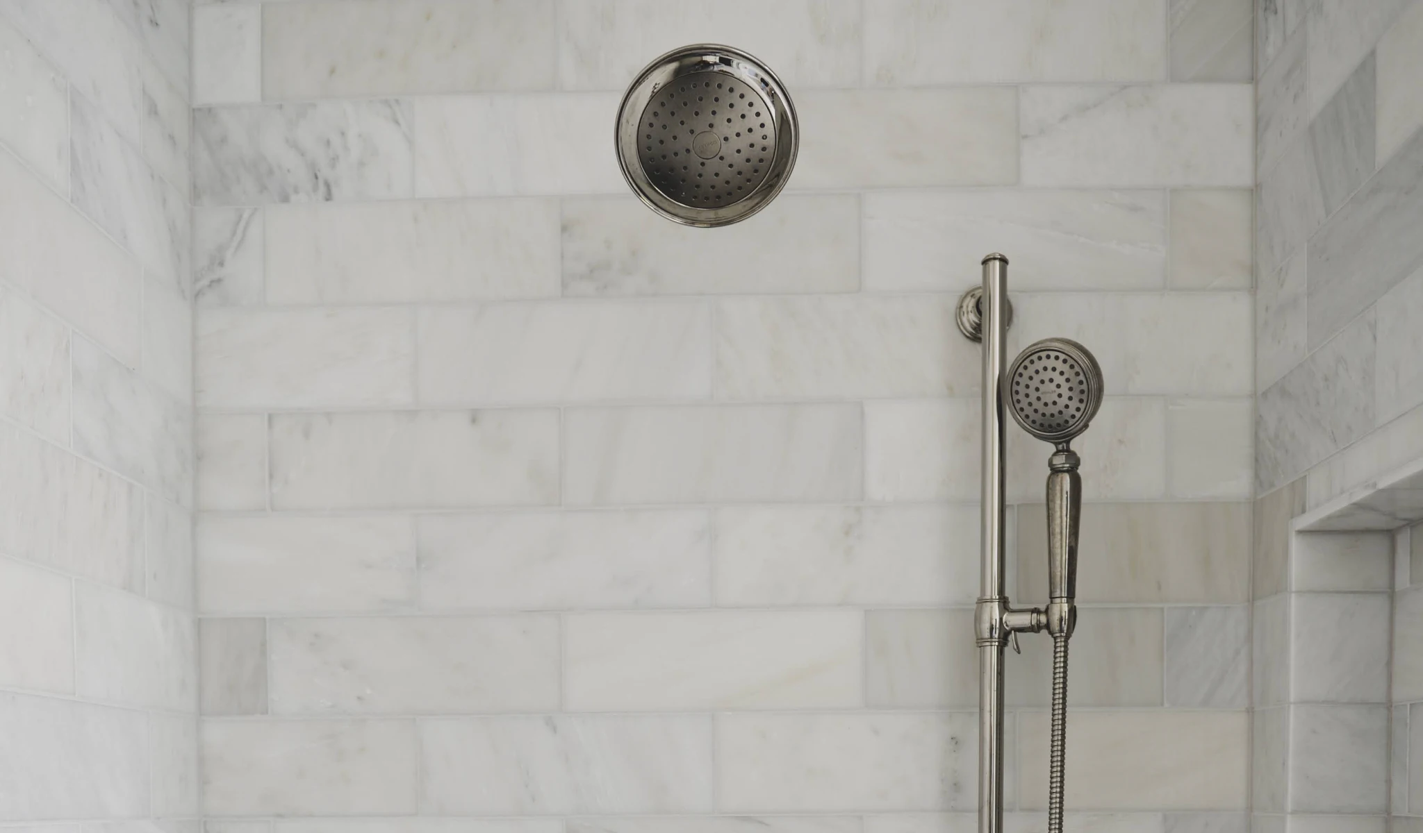 A marble shower with a custom shower head.
