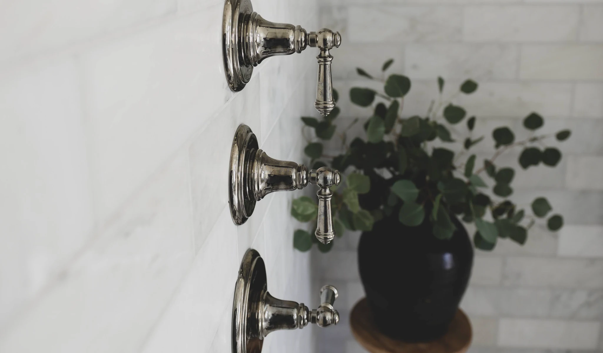 Three faucets hanging on a wall in a bathroom installed by home builders.
