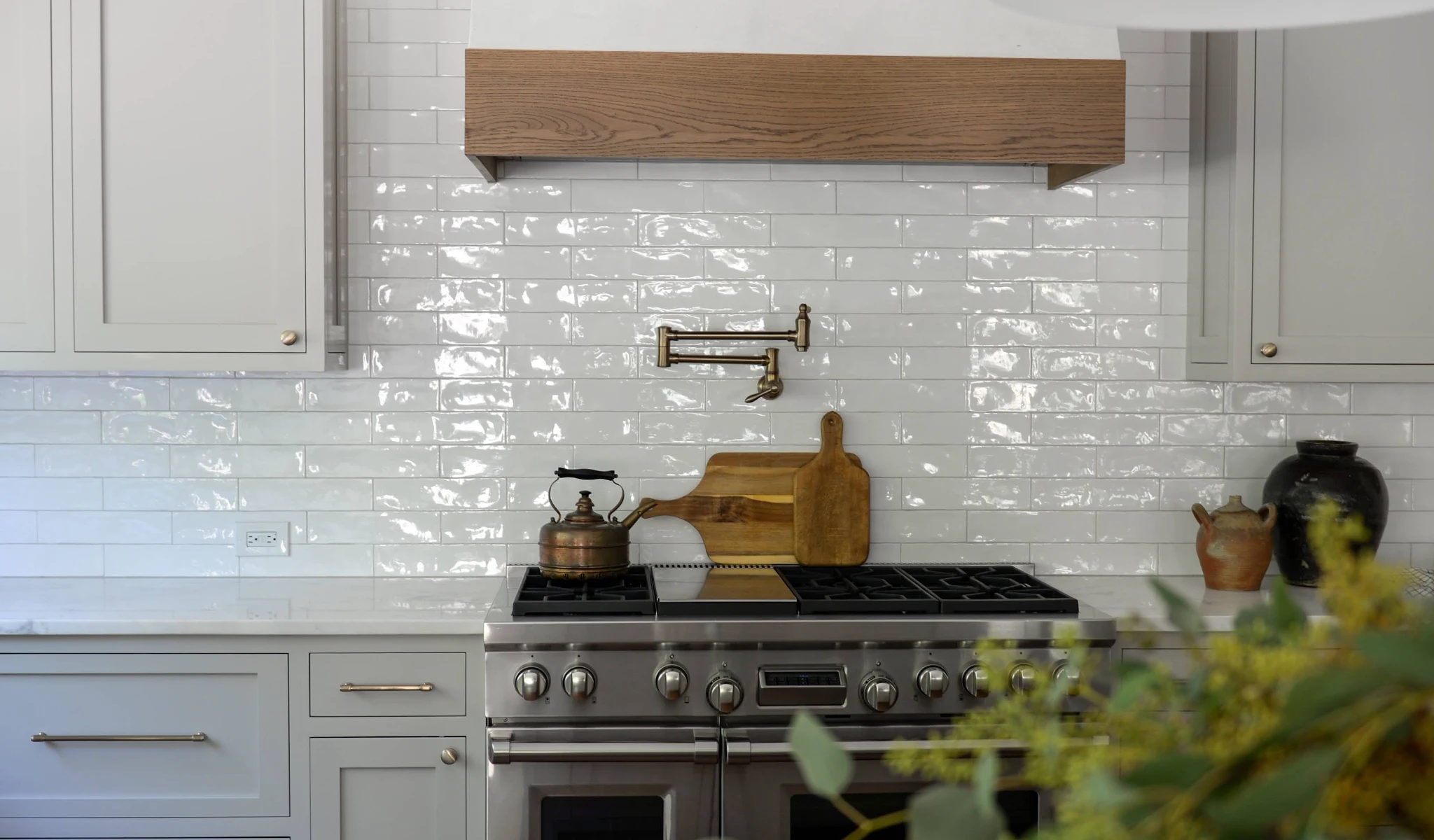 A kitchen with a white tile backsplash designed by a home builder.