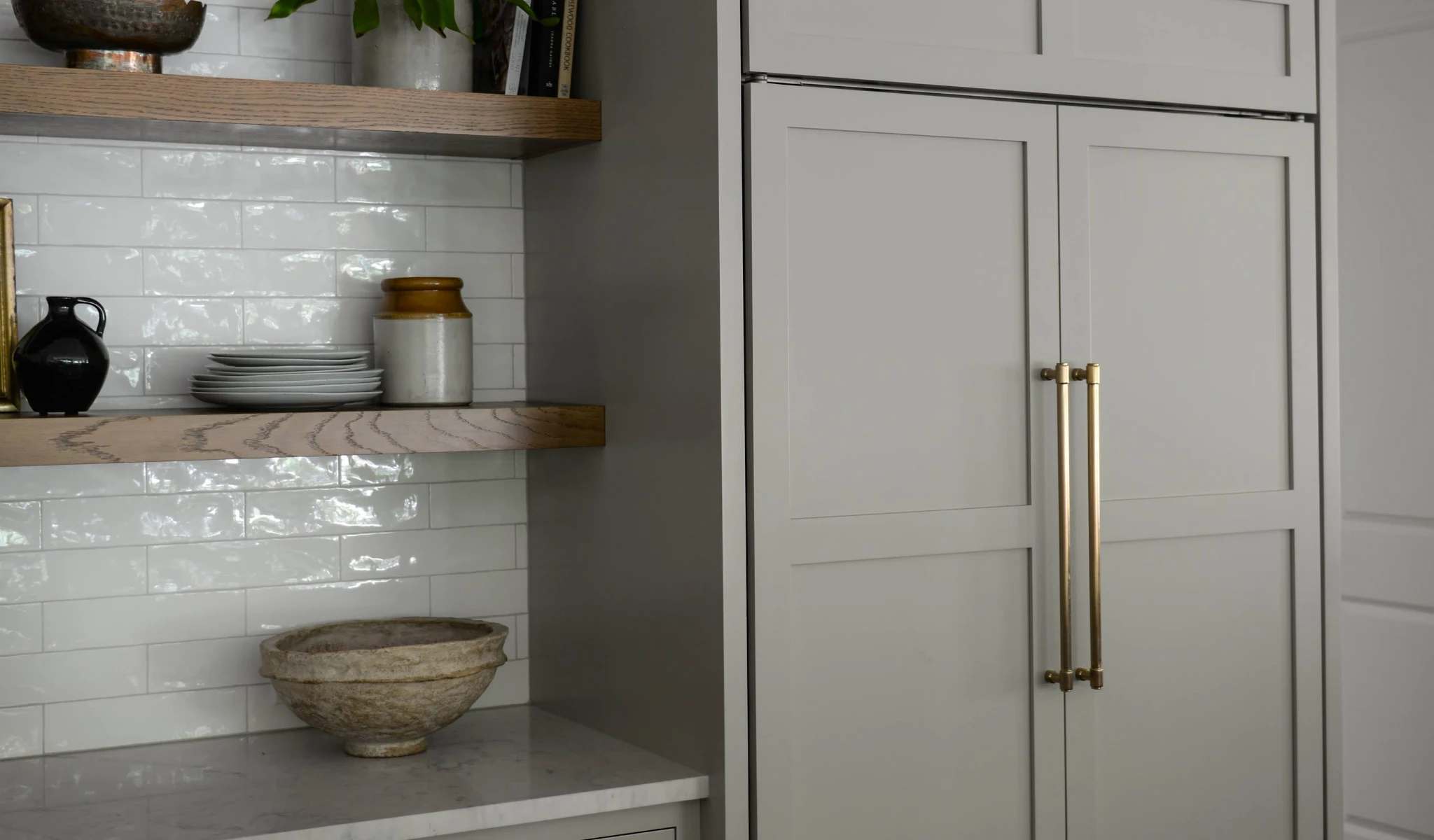 A kitchen with a grey refrigerator and wooden shelves in a new home construction.