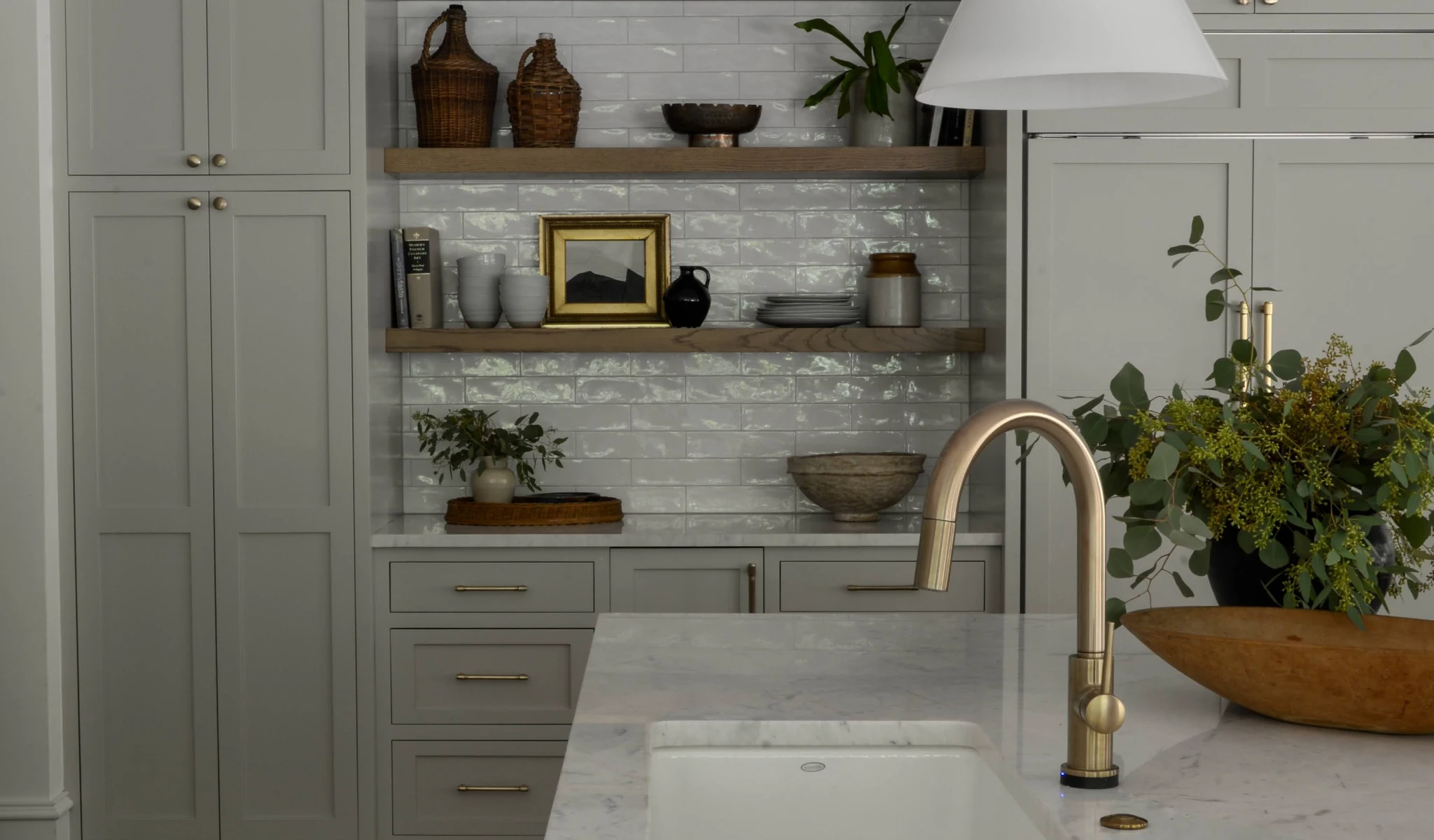 A kitchen with white cabinets and a gold faucet.