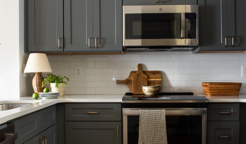A kitchen with gray cabinets and new stainless steel appliances.