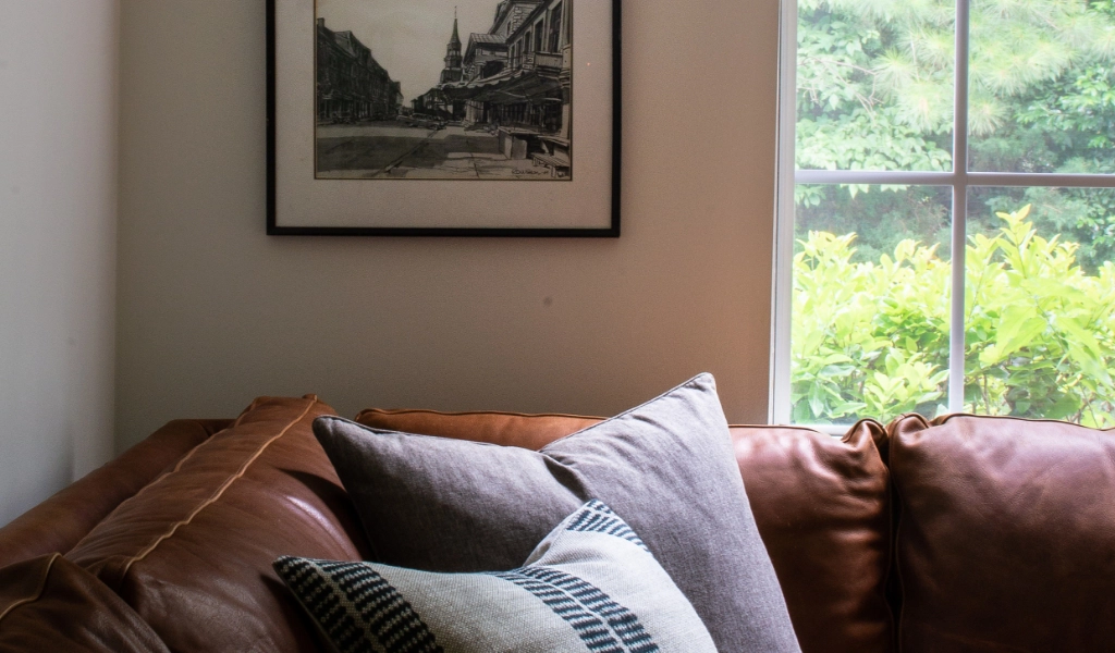 A brown leather couch in front of a window.