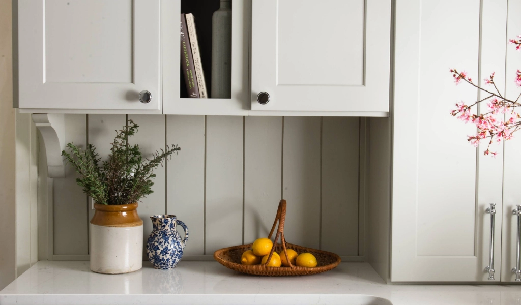 A kitchen with white cabinets and a bowl of lemons.