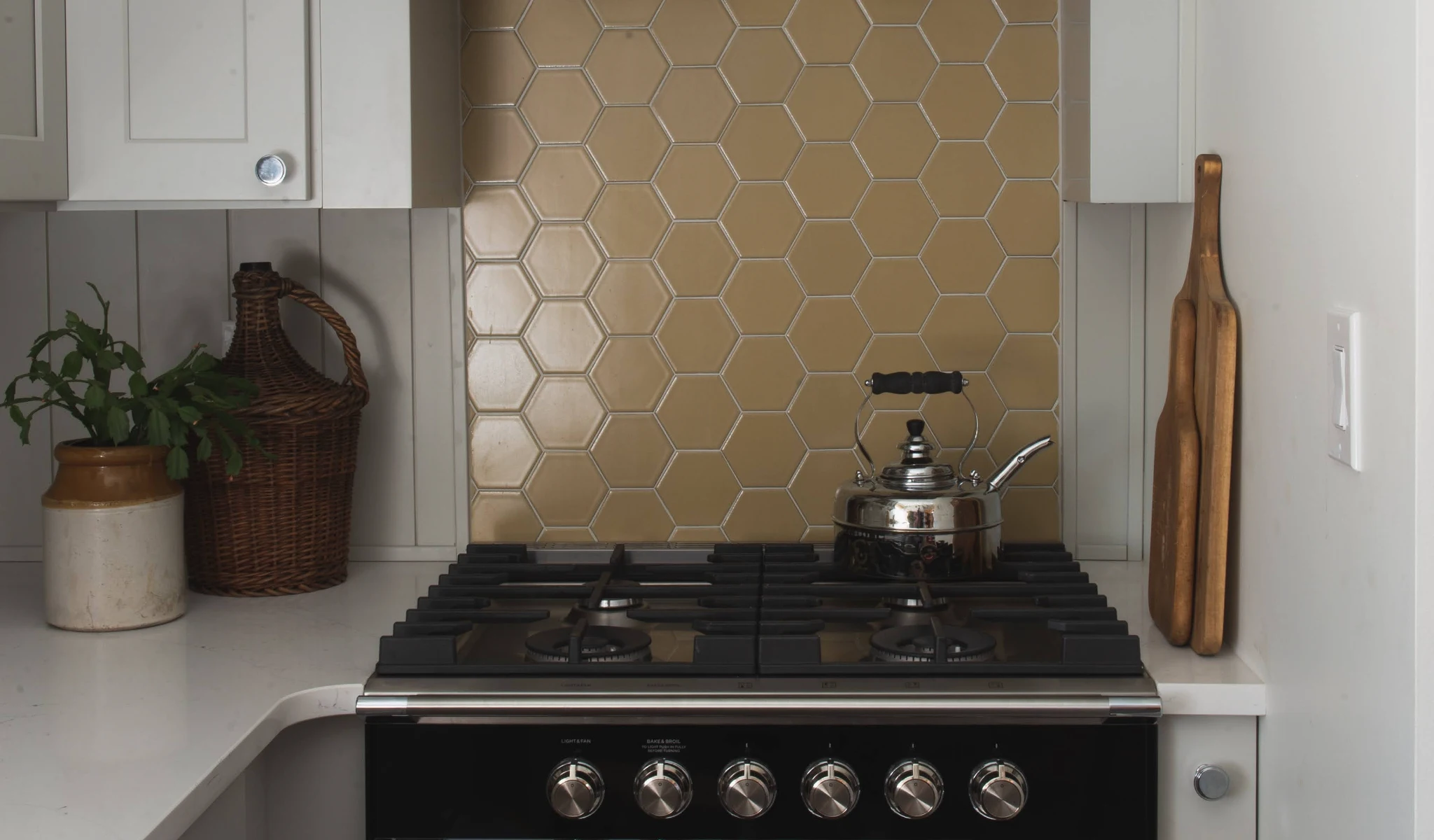 A kitchen with a stove and custom tiled backsplash.