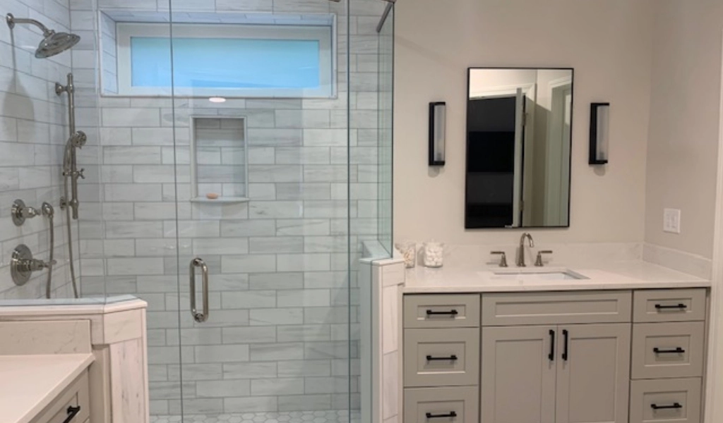 A white bathroom with a glass shower stall designed by home builders.