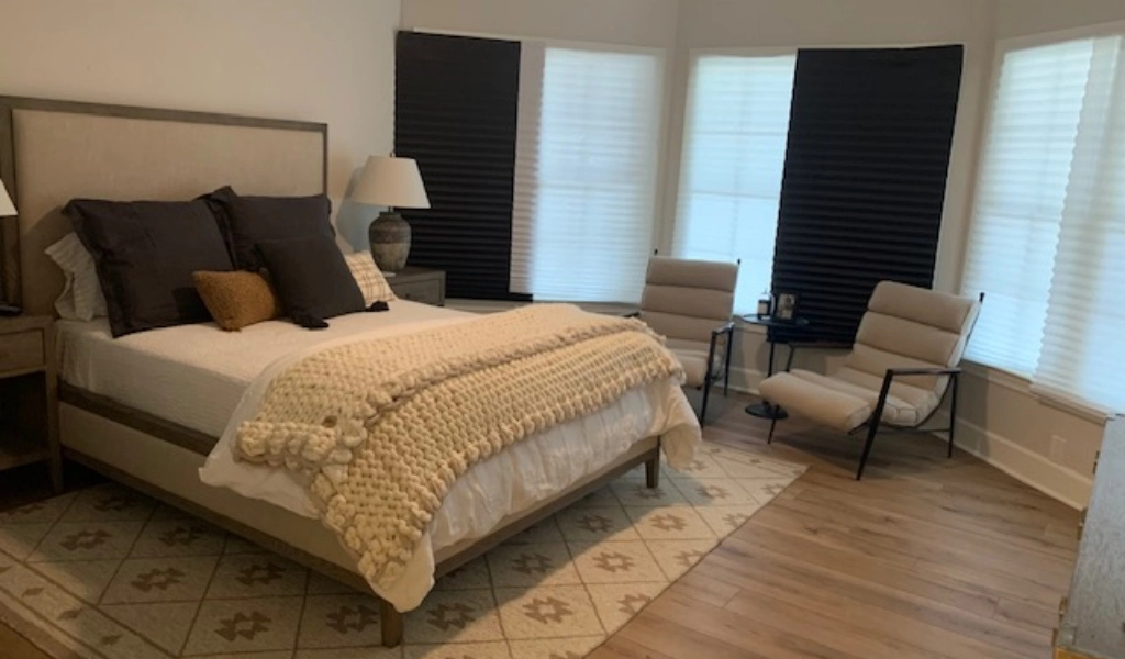 A bedroom with a bed and chair after a home remodel.