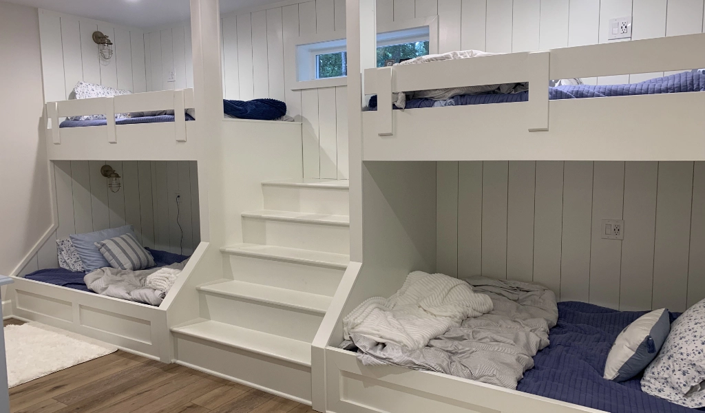 A white bunk bed in a room with stairs in a new home construction.