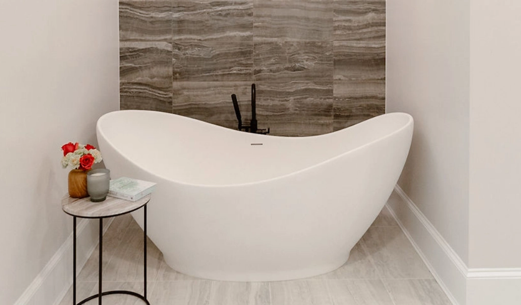 A white bathtub in a small bathroom designed by a home designer.