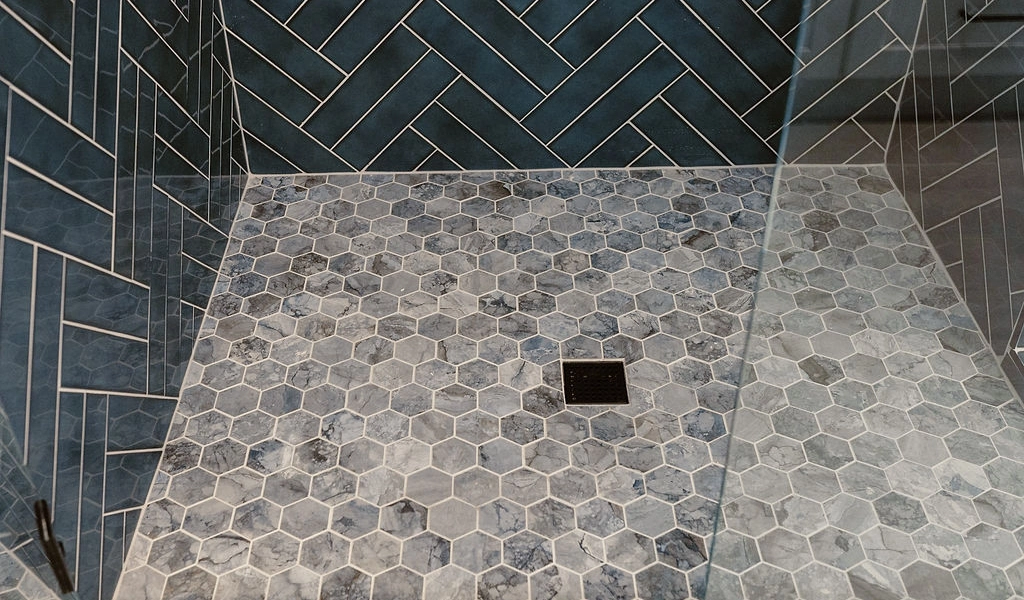 A blue tiled shower with a glass door.