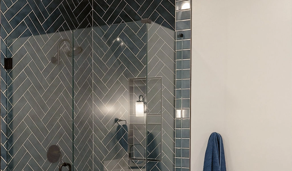 A bathroom with a glass shower door and blue tile in a new home construction.