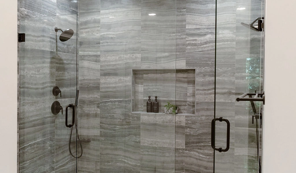 A bathroom with a stylish glass shower door, designed by home builders.