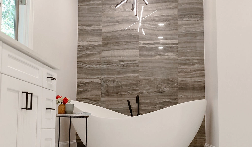 A modern bathroom with a white tub and chandelier.