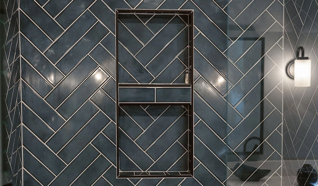 A bathroom with a blue herringbone tiled wall.
