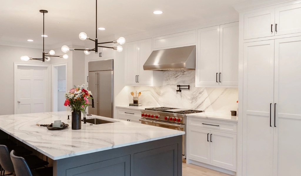 A kitchen with white cabinets and marble countertops designed by a custom home builder.