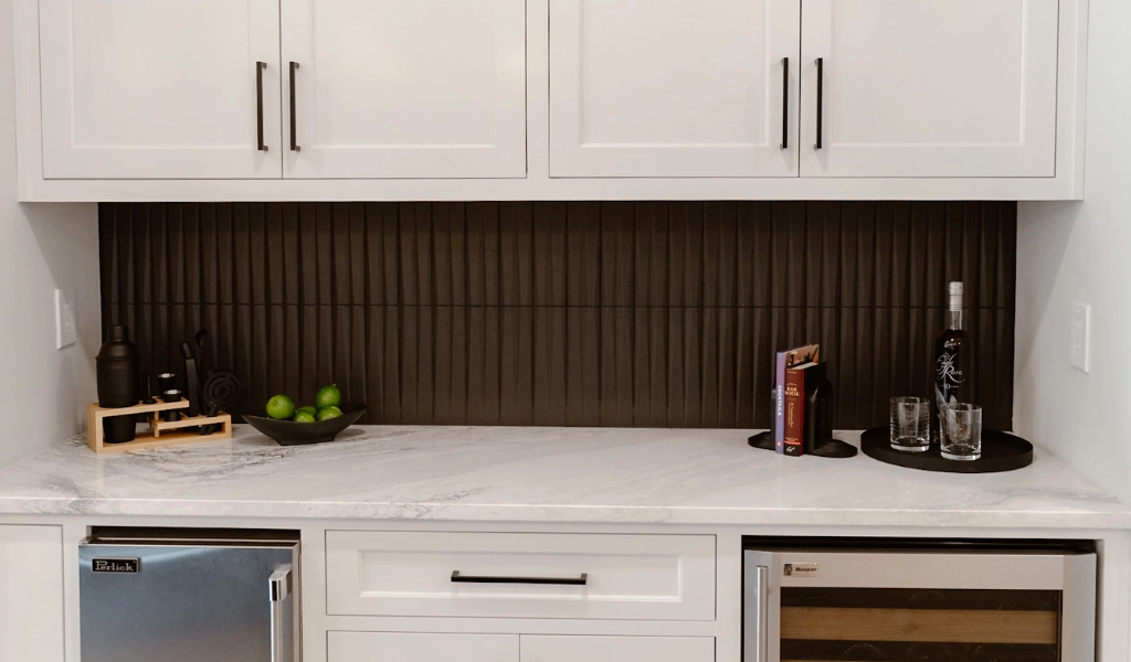 A white kitchen with marble countertops and wine cooler.