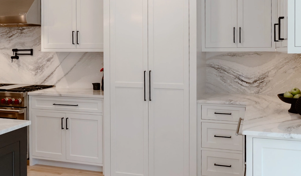 A kitchen with white cabinets and marble countertops.