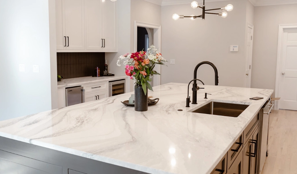 A white kitchen with marble counter top designed by home builders.