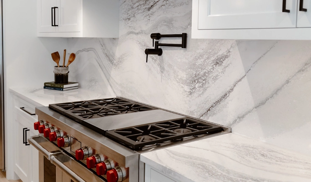 A kitchen with white cabinets and new marble countertops.