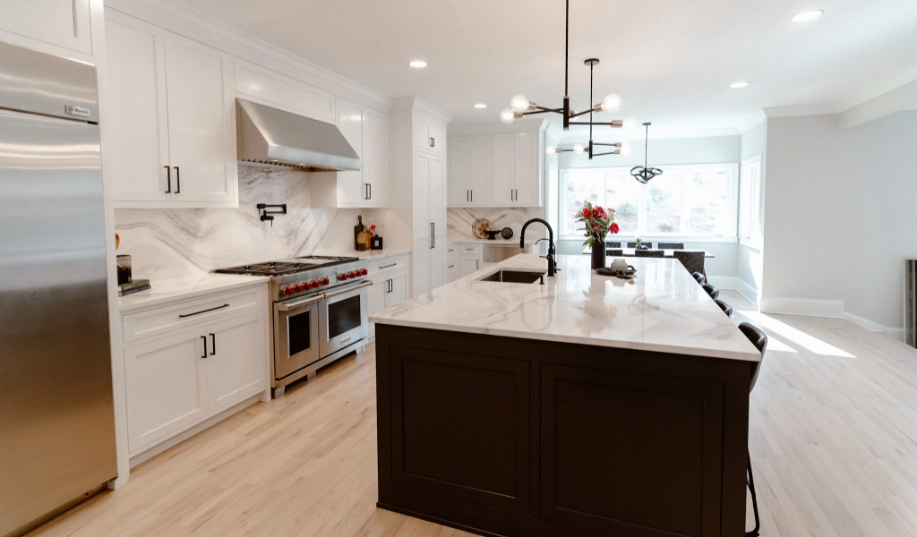 A kitchen with white cabinets and stainless steel appliances designed by a custom home builder.