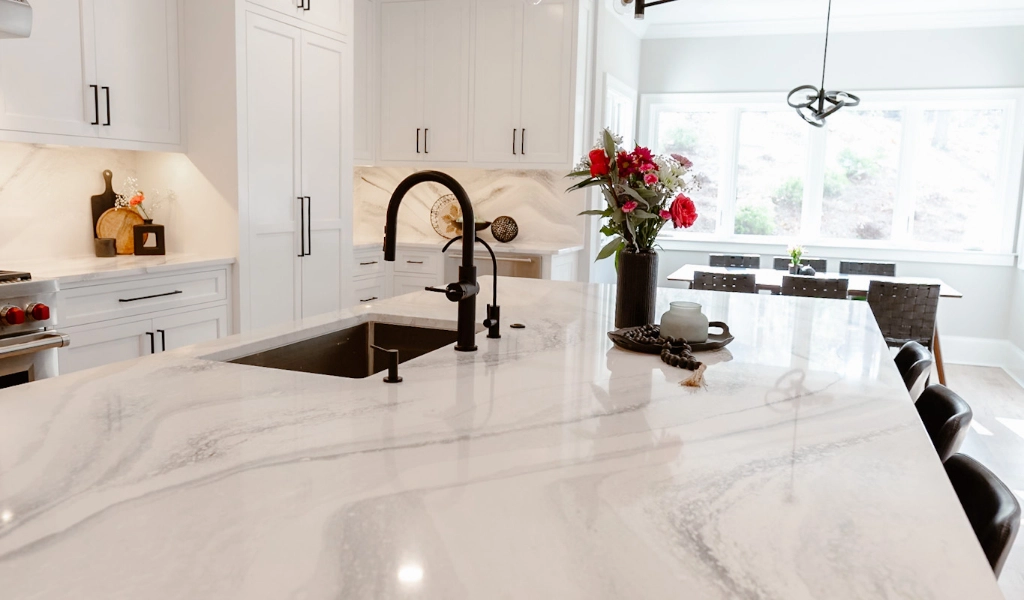 A white kitchen with marble countertops designed by a home designer.