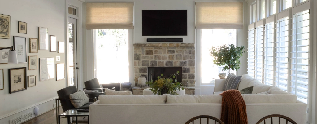 A living room with white furniture and a stone fireplace.