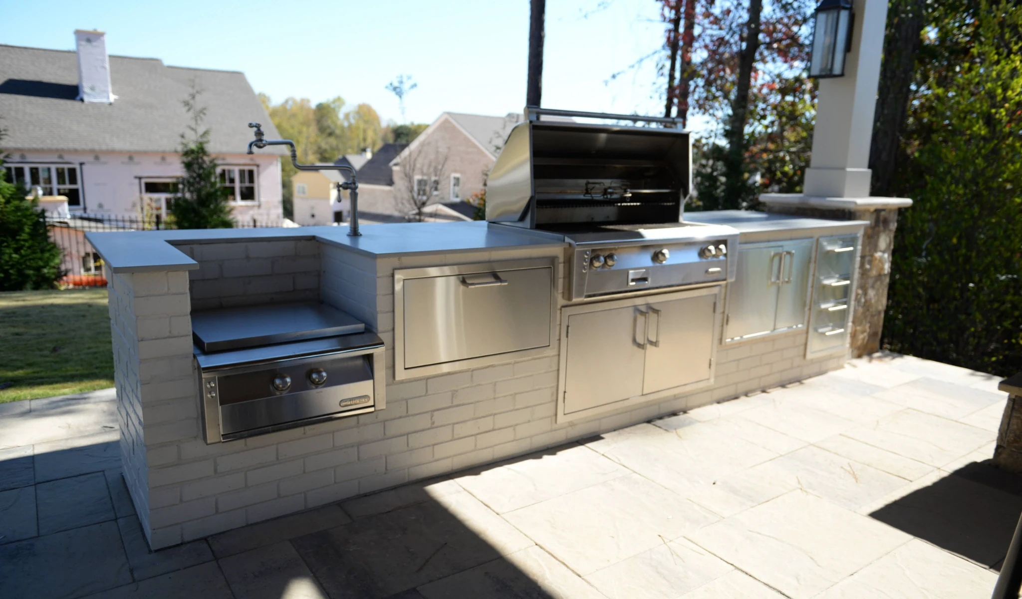 A custom outdoor kitchen with stainless steel appliances designed by a home designer.