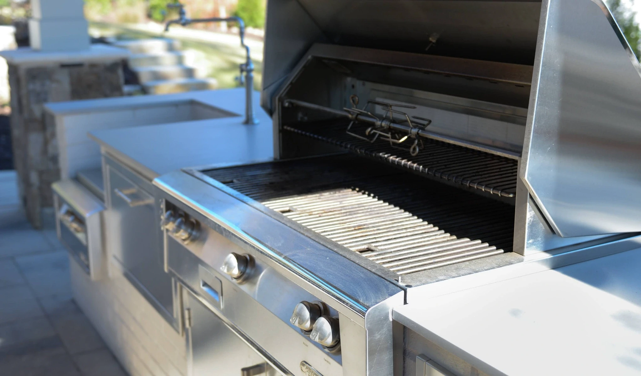 An outdoor kitchen with a stainless steel grill.
